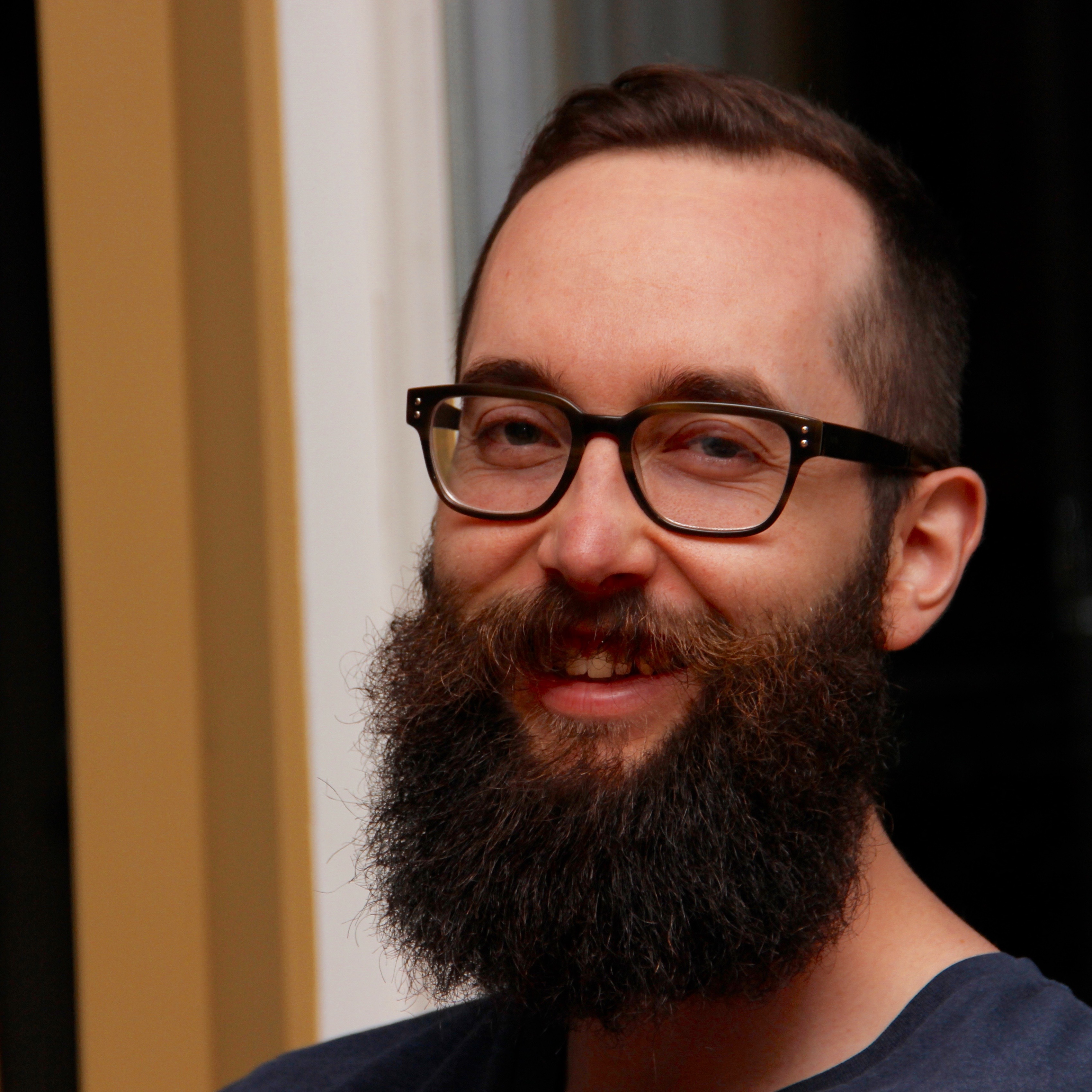 a picture of a bearded white man with glasses, smiling at the camera